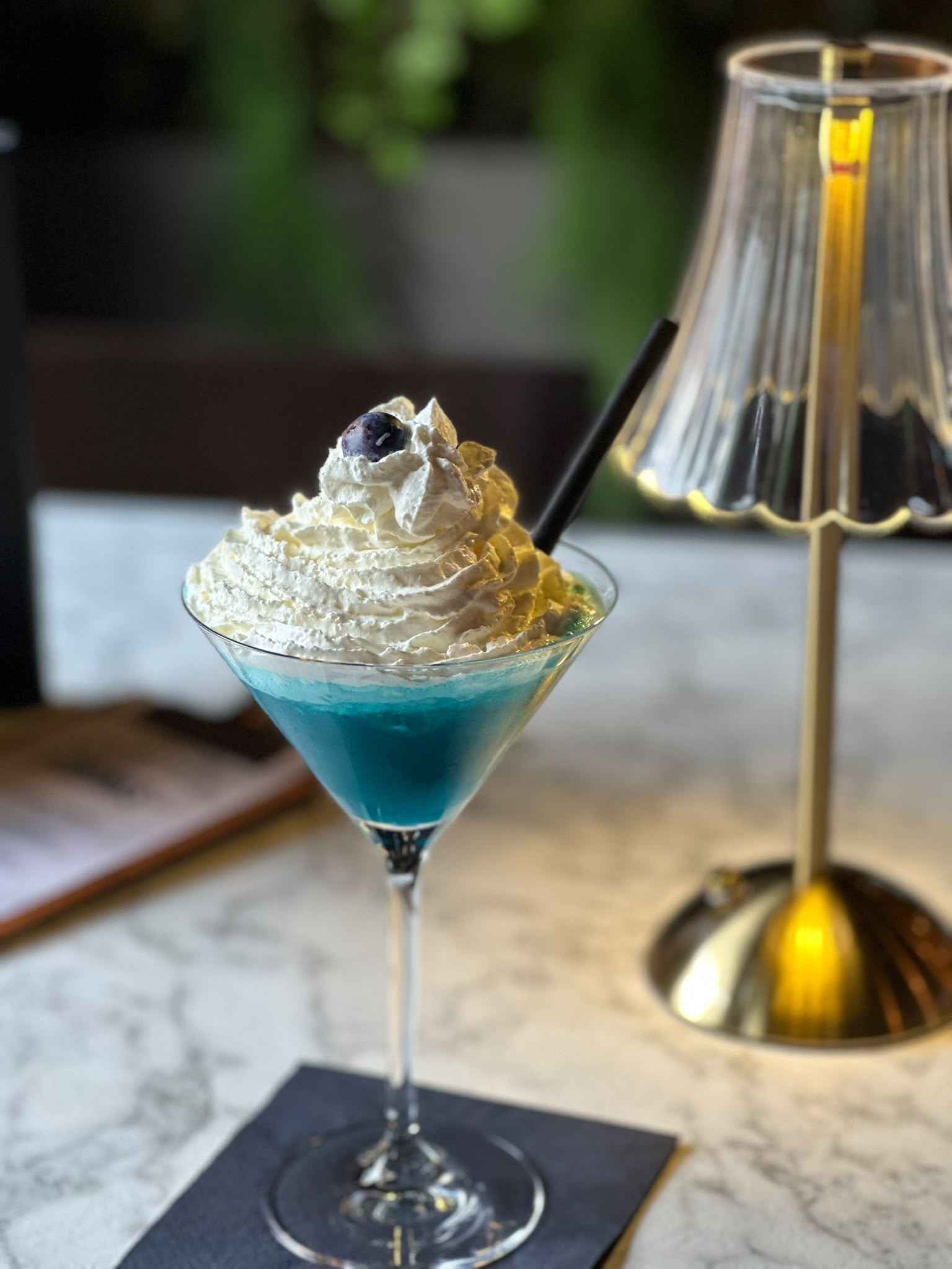 Verspielter blauer Cocktail mit Sahnehaube